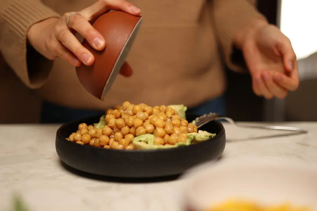 Į dubenėlį sudedame avokadą, avinžirnius bei užpilame alyvuogių aliejaus